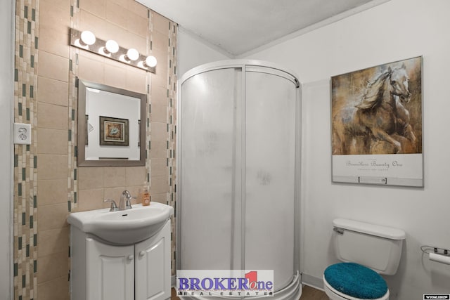 full bath featuring vanity, a stall shower, decorative backsplash, tile walls, and toilet