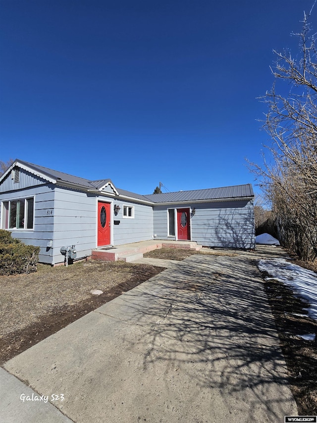 view of front of home with driveway, metal roof, and entry steps