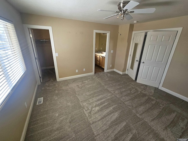 unfurnished bedroom featuring dark colored carpet, a closet, visible vents, and baseboards