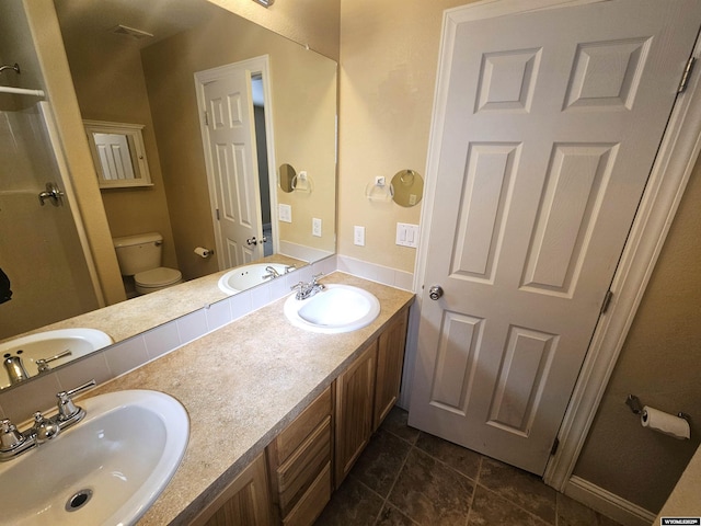 bathroom featuring double vanity, a sink, and toilet