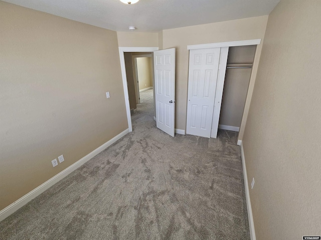 unfurnished bedroom with a closet, baseboards, and carpet flooring