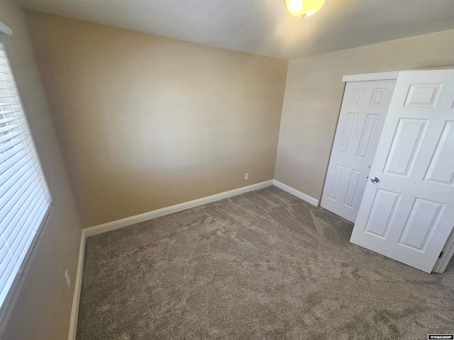 unfurnished bedroom with a closet, carpet, and baseboards