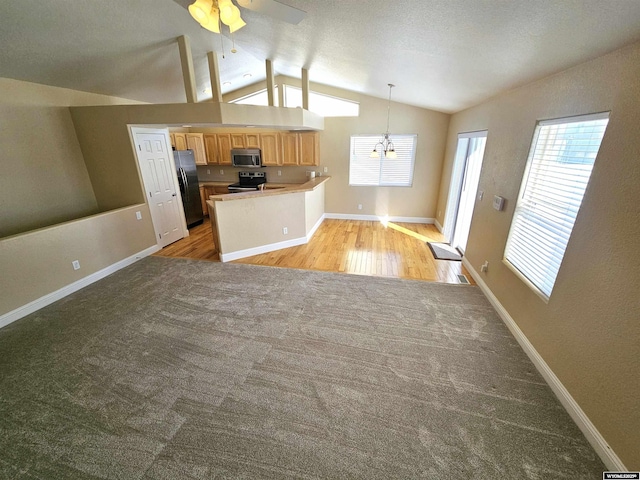 kitchen with a peninsula, baseboards, vaulted ceiling, appliances with stainless steel finishes, and pendant lighting