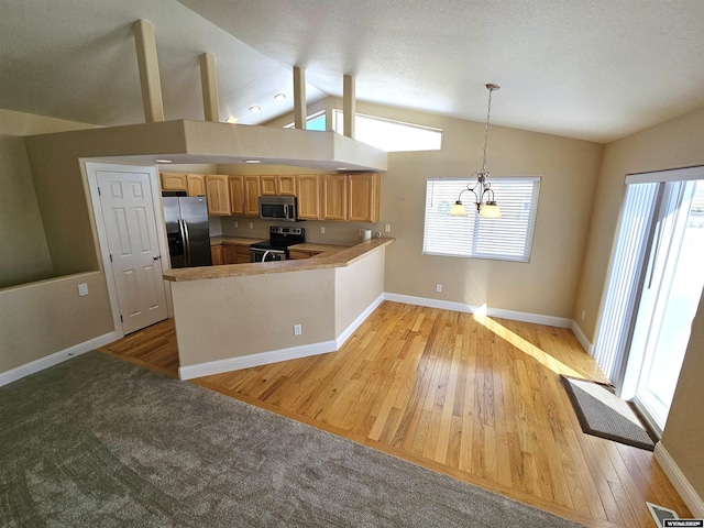 kitchen featuring lofted ceiling, stainless steel appliances, light wood finished floors, and plenty of natural light