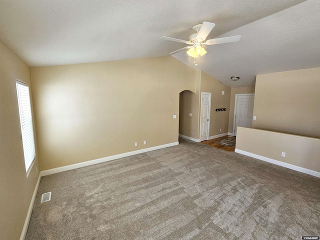 carpeted spare room with arched walkways, lofted ceiling, a ceiling fan, visible vents, and baseboards