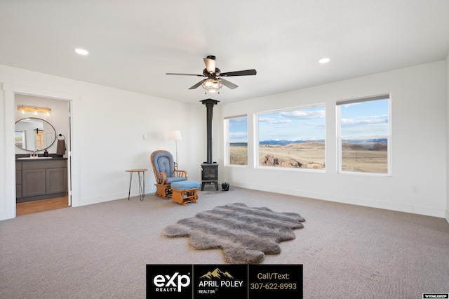 sitting room with carpet floors, a wood stove, plenty of natural light, and recessed lighting