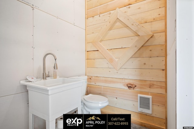 bathroom with toilet, wooden walls, visible vents, and vanity