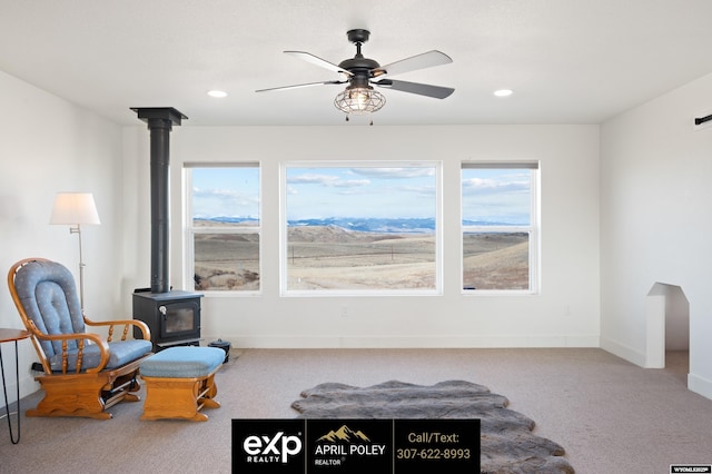 sitting room with a wood stove, a healthy amount of sunlight, and carpet