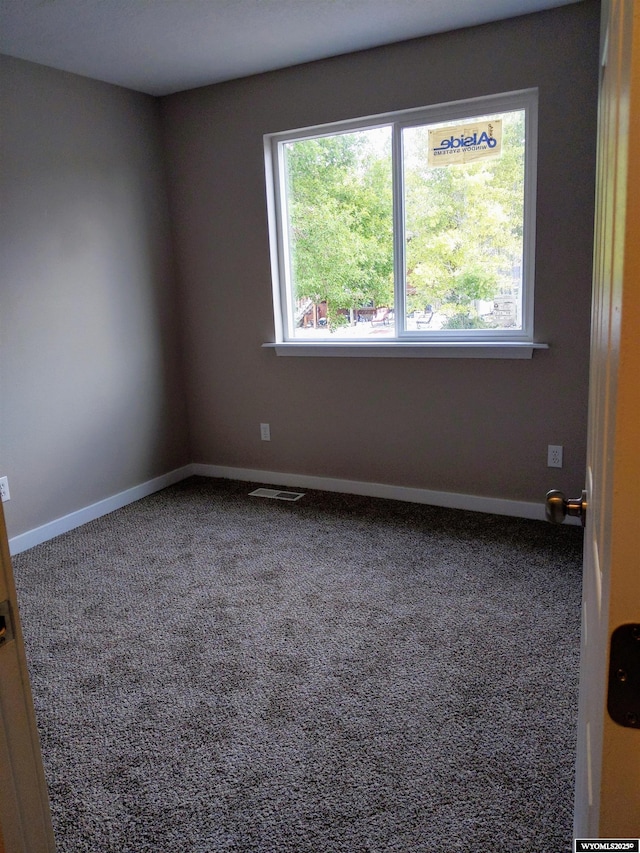 unfurnished room with carpet, visible vents, and baseboards