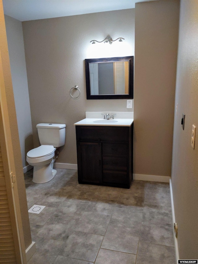 half bath with toilet, baseboards, and vanity