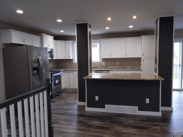 kitchen featuring stainless steel appliances, light stone counters, visible vents, and white cabinets