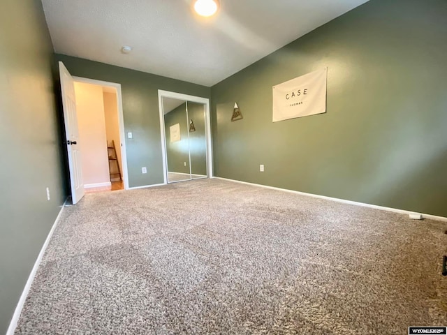 unfurnished bedroom with carpet, a closet, and baseboards