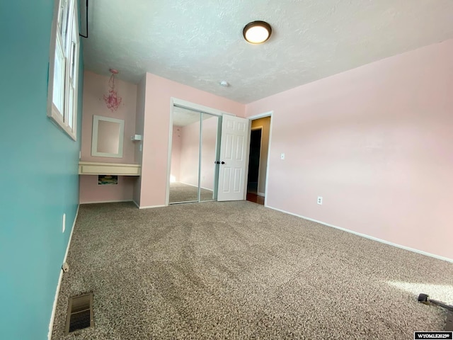 unfurnished bedroom with carpet, baseboards, visible vents, a closet, and a textured ceiling