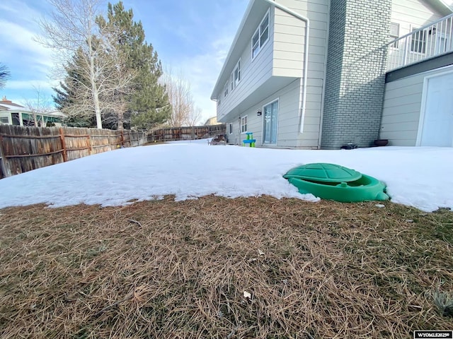 snowy yard with a fenced backyard