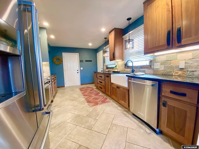 kitchen with dark countertops, backsplash, brown cabinets, stainless steel appliances, and a sink