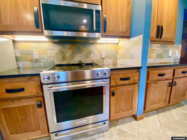 kitchen with dark countertops, decorative backsplash, stainless steel appliances, and light tile patterned floors