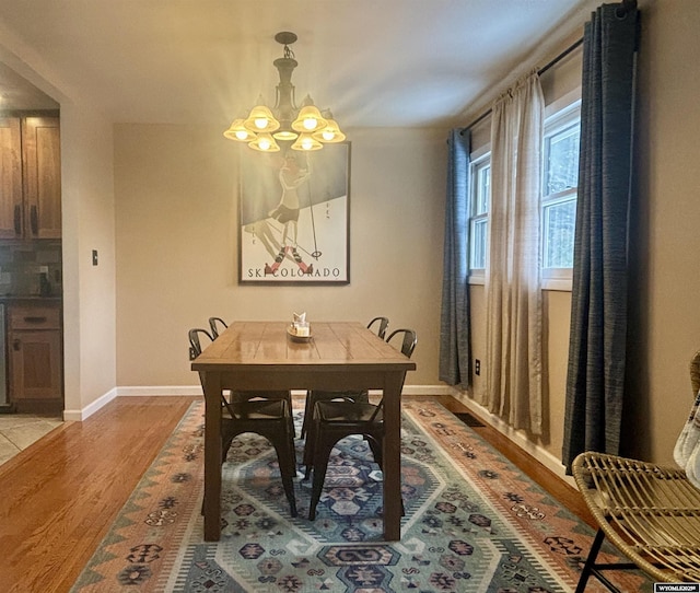 dining area featuring a notable chandelier, baseboards, and light wood finished floors