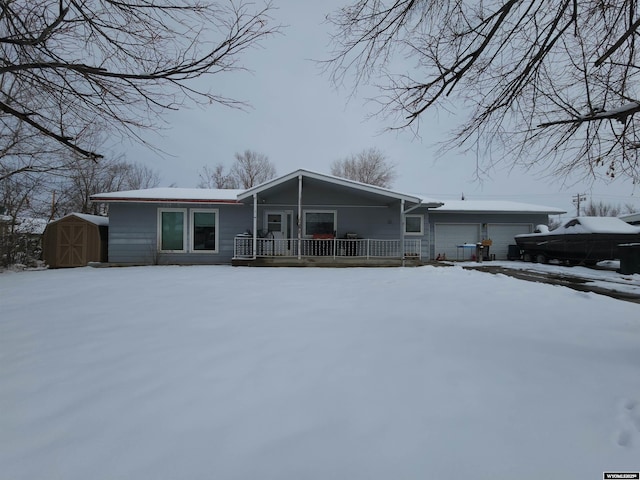 ranch-style home featuring a storage shed, a porch, an outdoor structure, and an attached garage