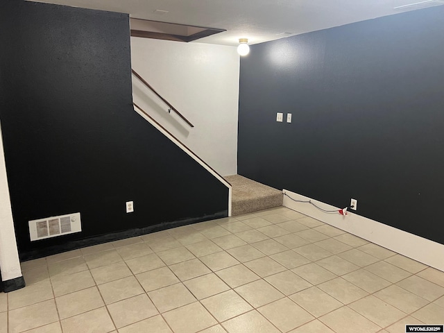 unfurnished room featuring tile patterned flooring, visible vents, and stairway