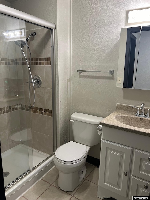 full bathroom featuring vanity, tile patterned flooring, a shower stall, toilet, and a textured wall