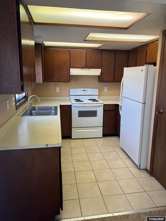 kitchen featuring under cabinet range hood, white appliances, light countertops, and a sink