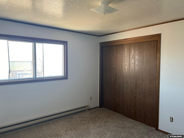 unfurnished room featuring carpet flooring, baseboard heating, and a textured ceiling