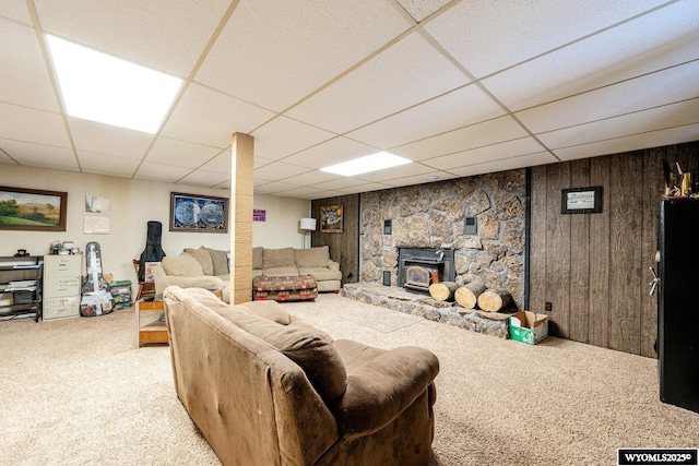 carpeted living area featuring wooden walls and a drop ceiling