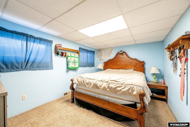 carpeted bedroom featuring a drop ceiling and visible vents