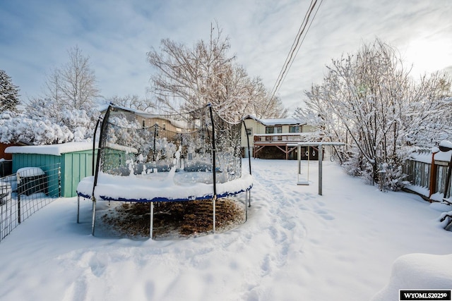 yard covered in snow with an outbuilding and fence