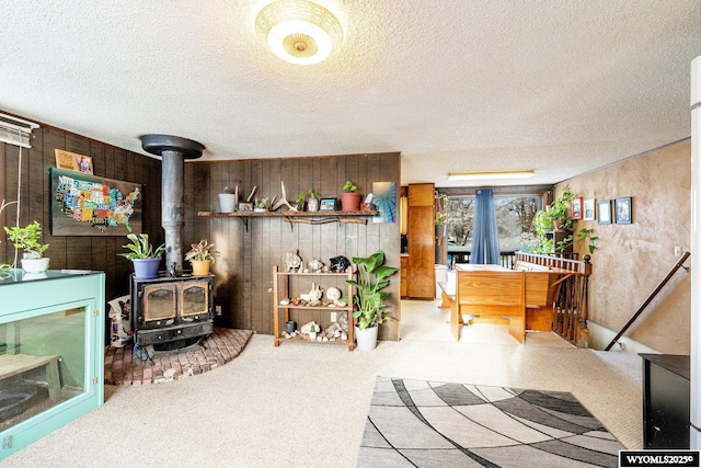 interior space with wood walls, a textured ceiling, and a wood stove