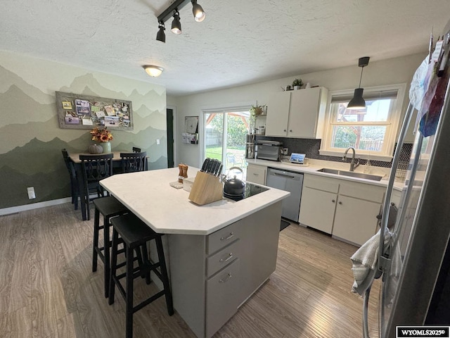 kitchen featuring dishwasher, light countertops, light wood finished floors, and a sink