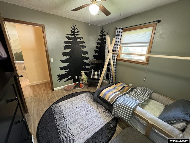 bedroom featuring a ceiling fan, wood finished floors, baseboards, and a textured ceiling