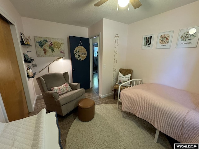 bedroom with a textured ceiling, a ceiling fan, baseboards, and wood finished floors