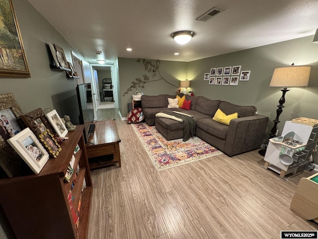 living area featuring visible vents, a textured ceiling, and wood finished floors