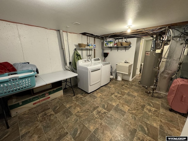 interior space featuring washing machine and clothes dryer, gas water heater, laundry area, stone finish floor, and a sink