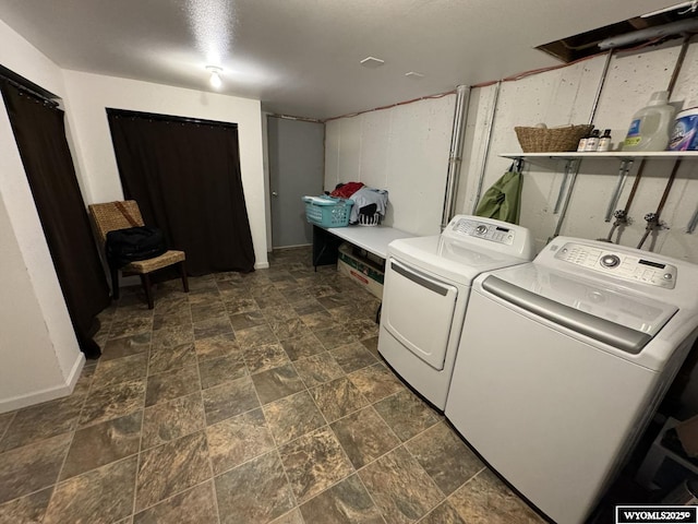 washroom featuring stone finish flooring, baseboards, and independent washer and dryer