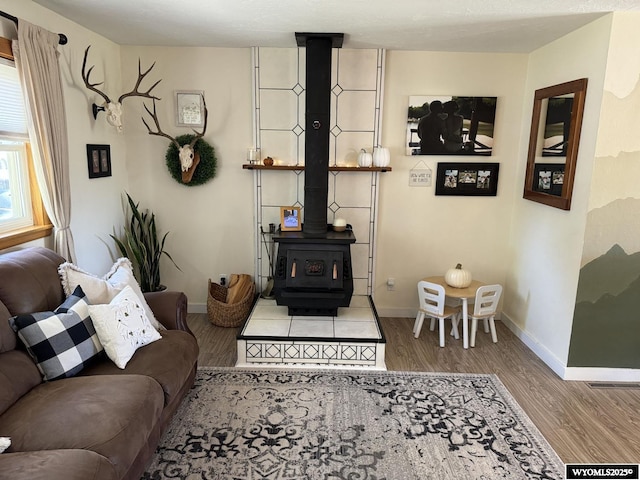 living area with visible vents, a wood stove, baseboards, and wood finished floors