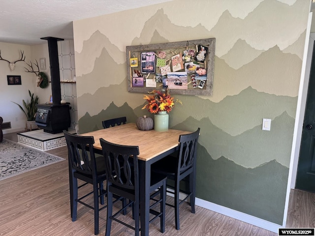 dining area with a wood stove, baseboards, and wood finished floors