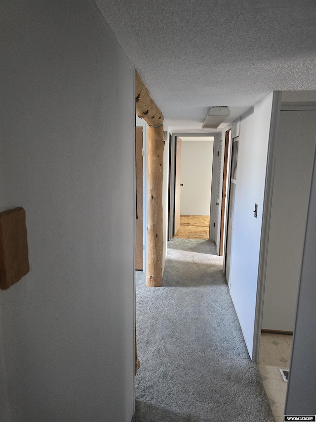 hallway with light colored carpet and a textured ceiling