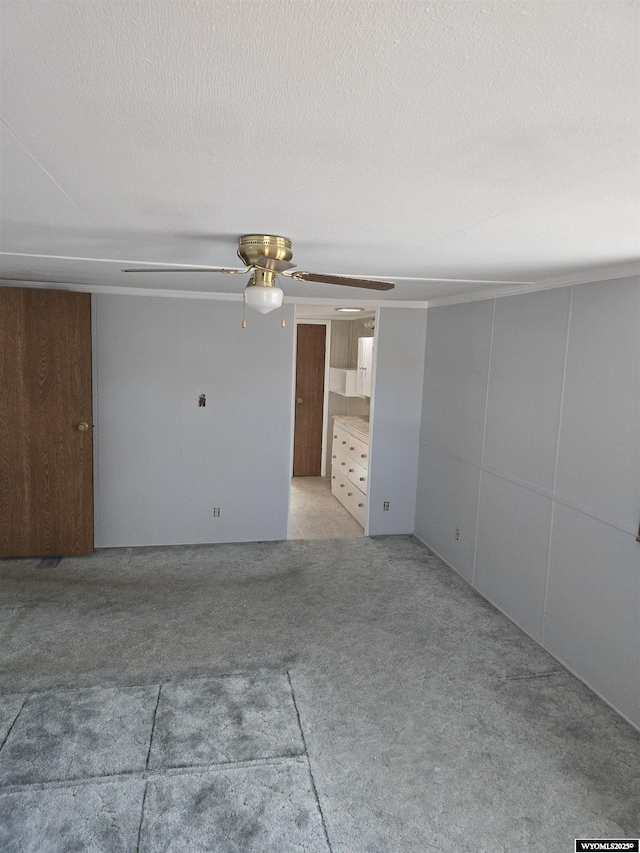 interior space with light colored carpet, ceiling fan, and a textured ceiling