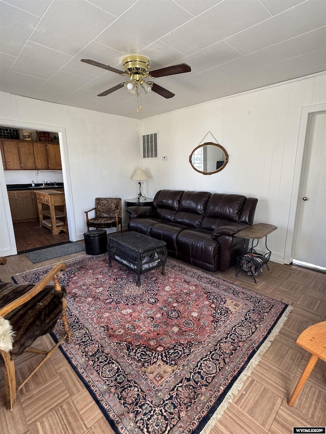 living room featuring a ceiling fan and visible vents