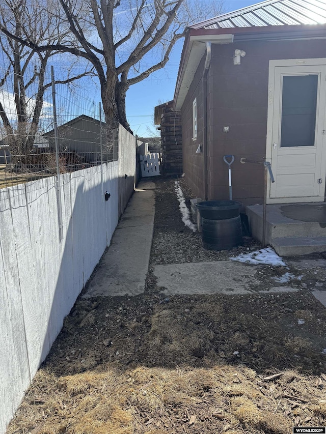 view of side of home with metal roof and fence