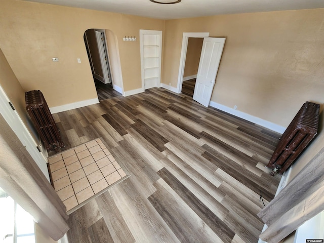 interior space featuring baseboards, arched walkways, and wood finished floors