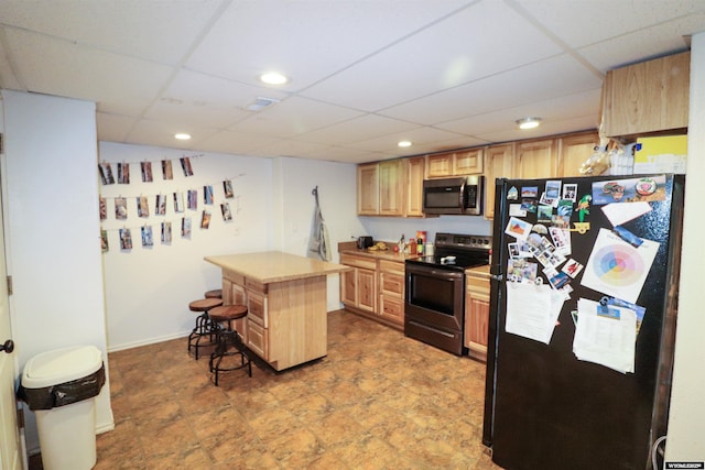 kitchen featuring light brown cabinetry, a kitchen breakfast bar, appliances with stainless steel finishes, light countertops, and a paneled ceiling