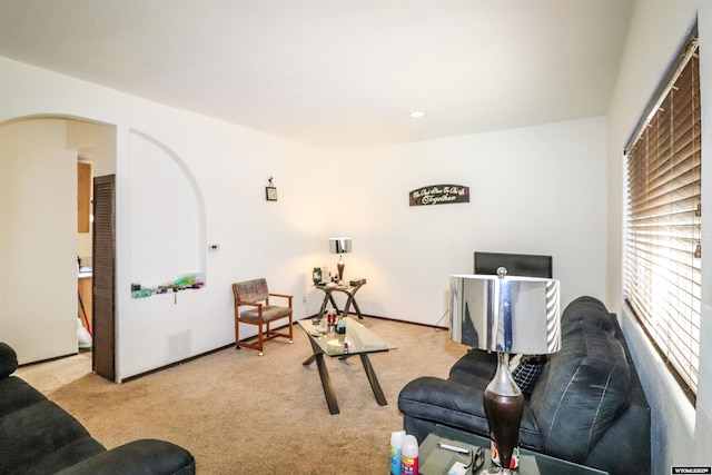 living room featuring carpet flooring, visible vents, and arched walkways