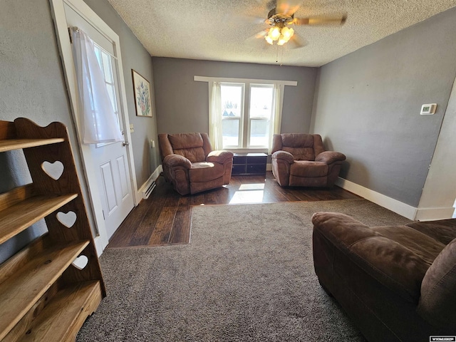 living area featuring baseboards, a textured ceiling, wood finished floors, and a ceiling fan