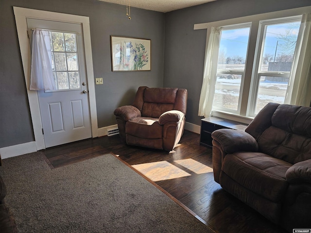 living area with a textured ceiling, wood finished floors, visible vents, and baseboards