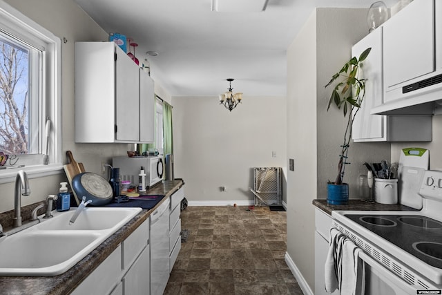 kitchen with stone finish floor, a sink, white cabinetry, white appliances, and baseboards