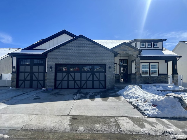 view of front of property with driveway, an attached garage, stone siding, board and batten siding, and brick siding