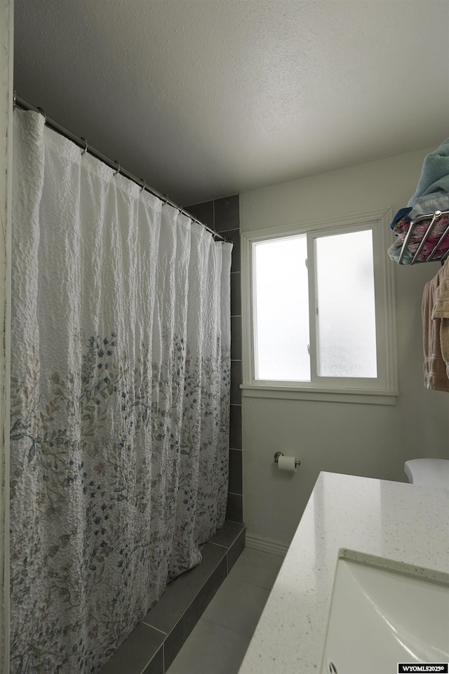 full bath featuring a textured ceiling, a shower with shower curtain, and a sink